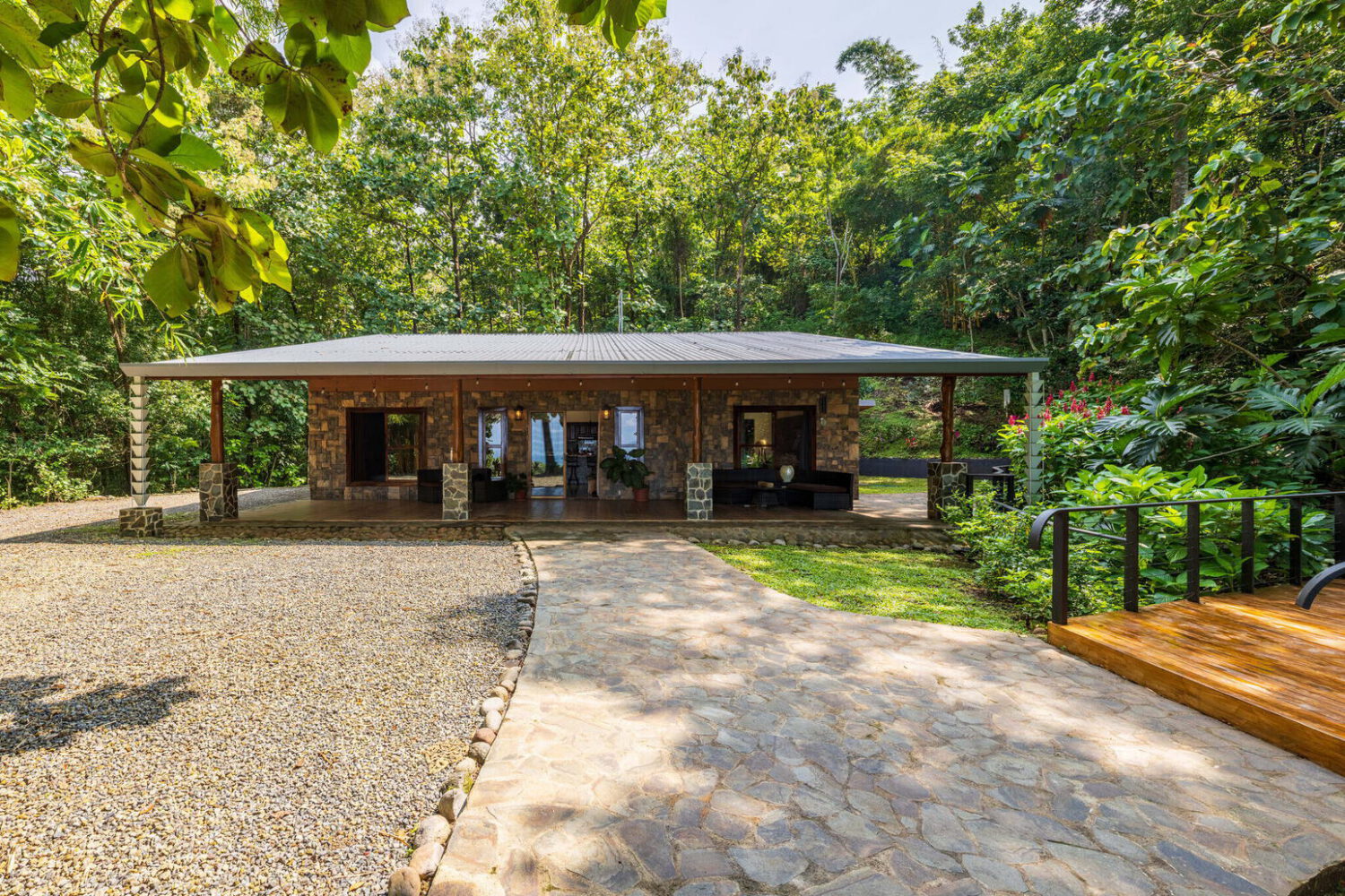 Covered stone terrace with rancho seating beside the garden
