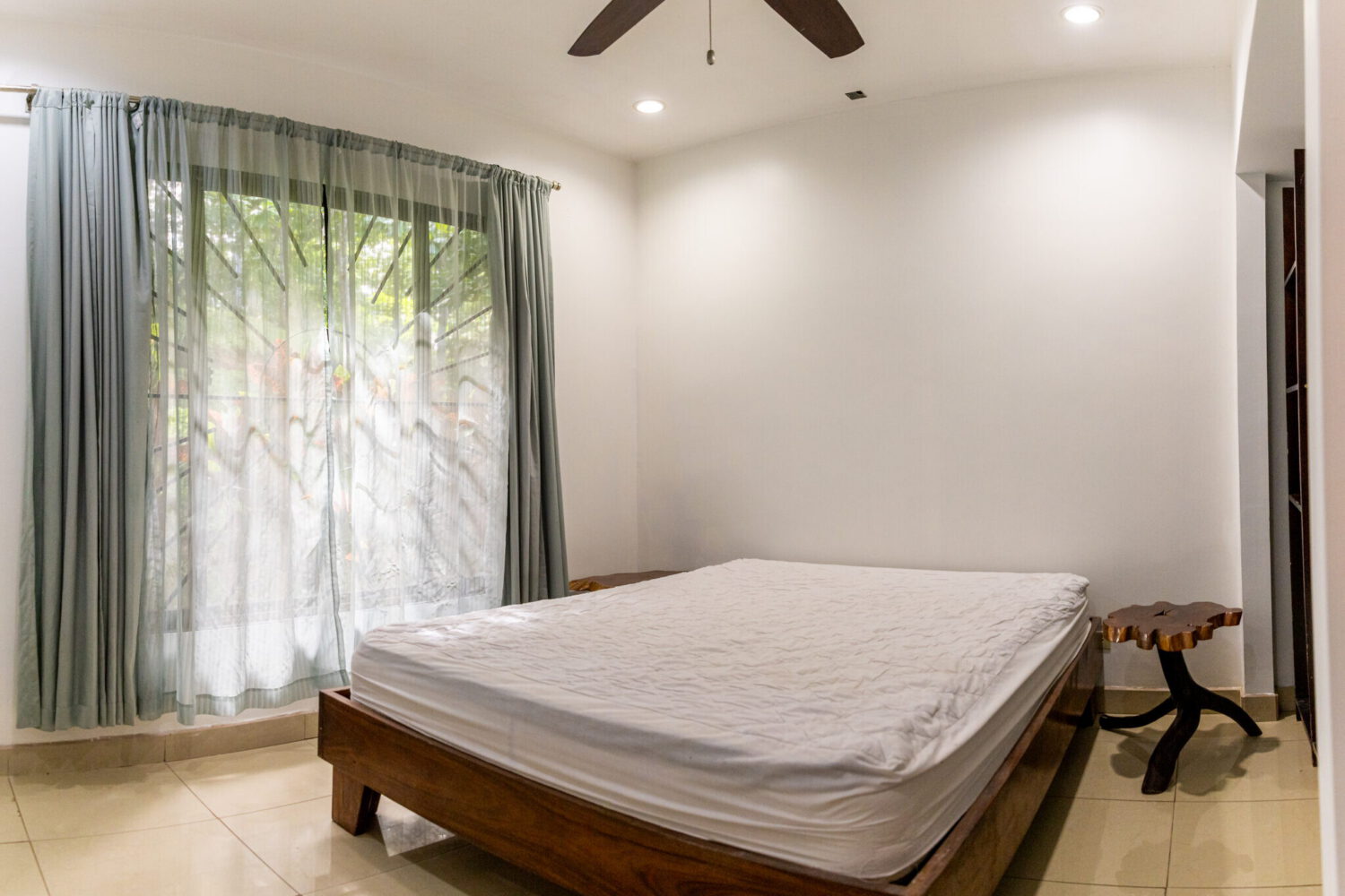 Bright bedroom with sheer curtains and garden access
