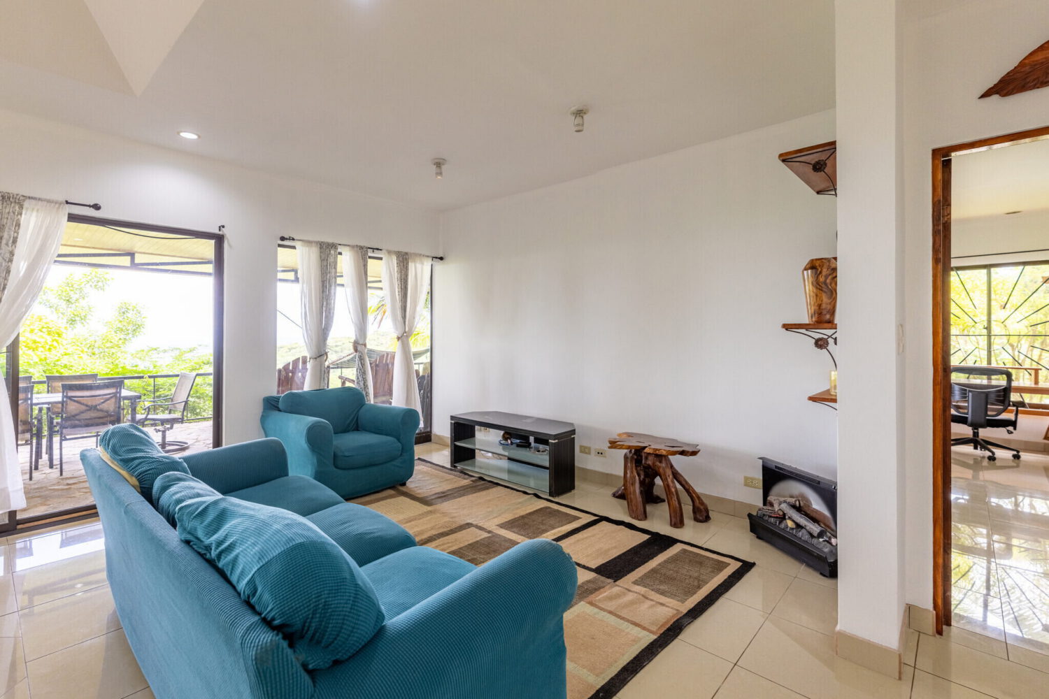 Living room with teal sofas opening to the terrace