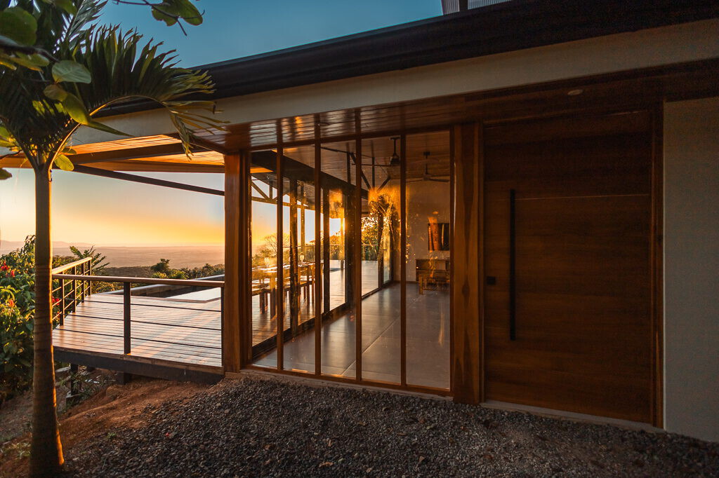 The home lit from within at dusk beside the pool