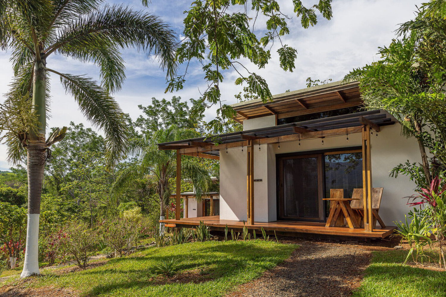 Compact guest villa with a covered porch among palms