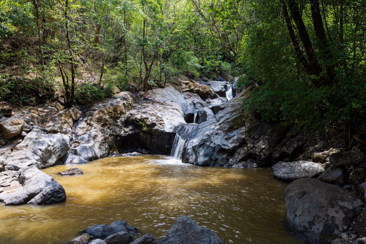 Waterfall spilling into a clear pool ringed by boulders
