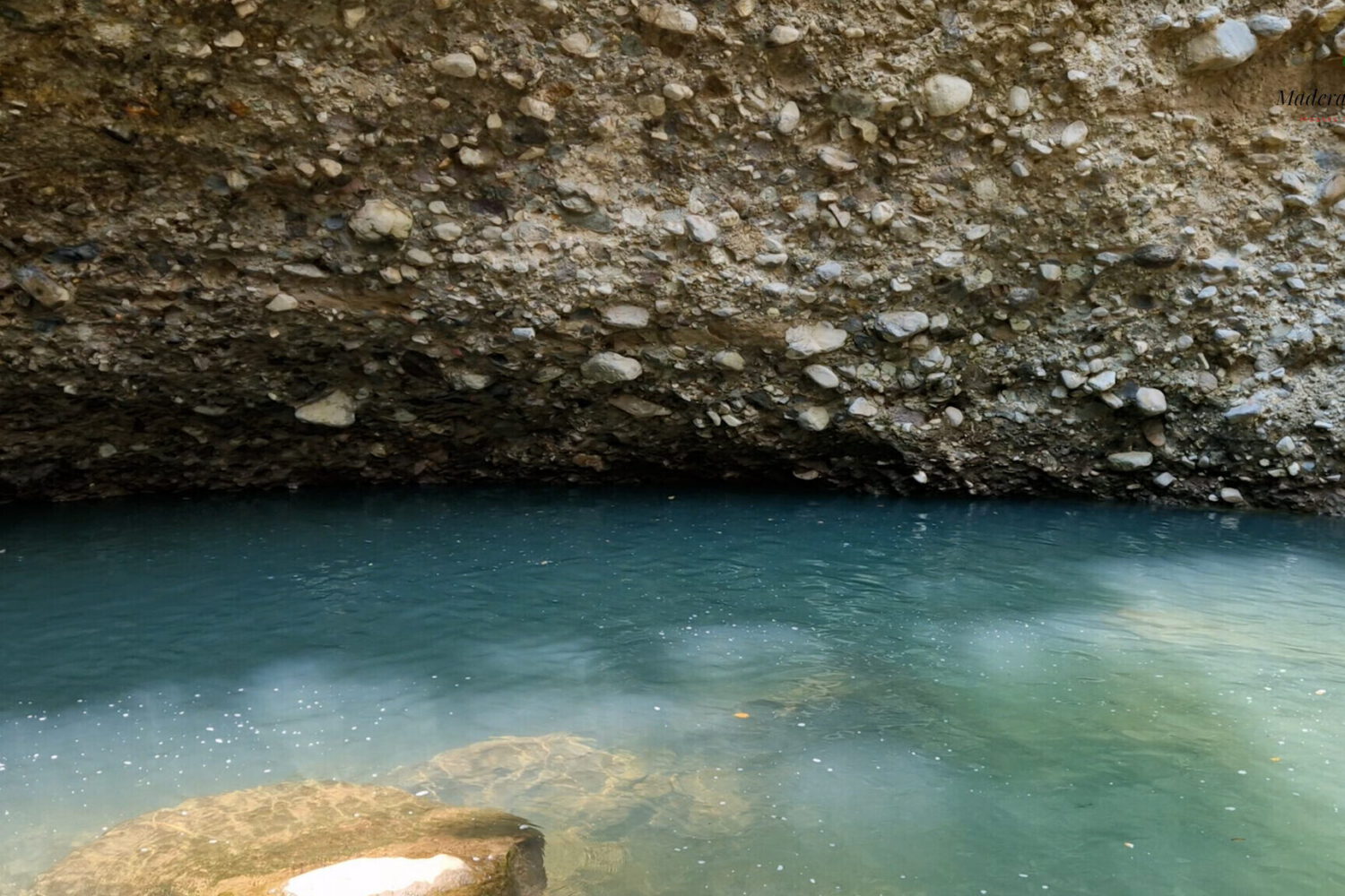 Turquoise river pool below a rock overhang