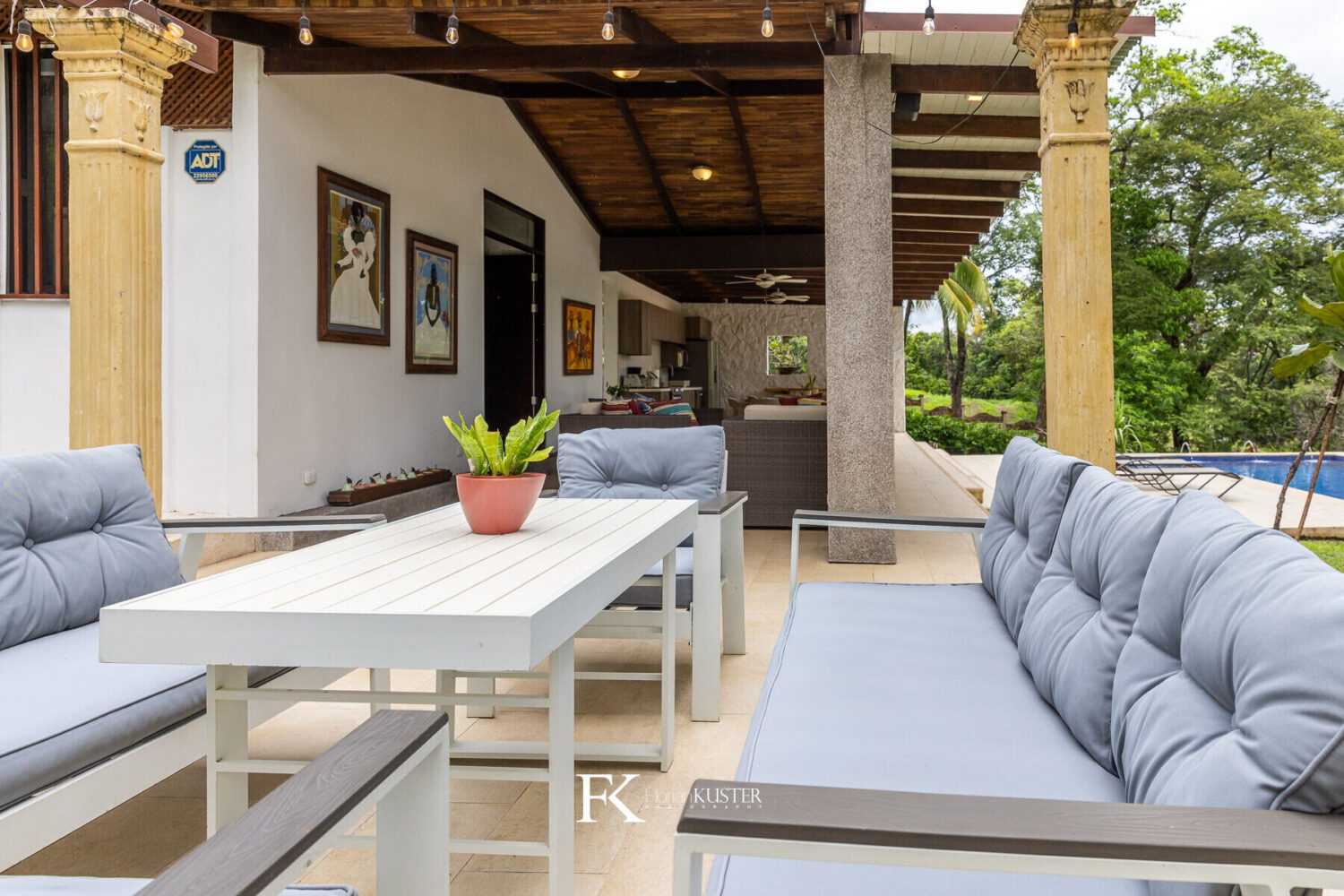 Open-air living room with sofas under an exposed timber roof