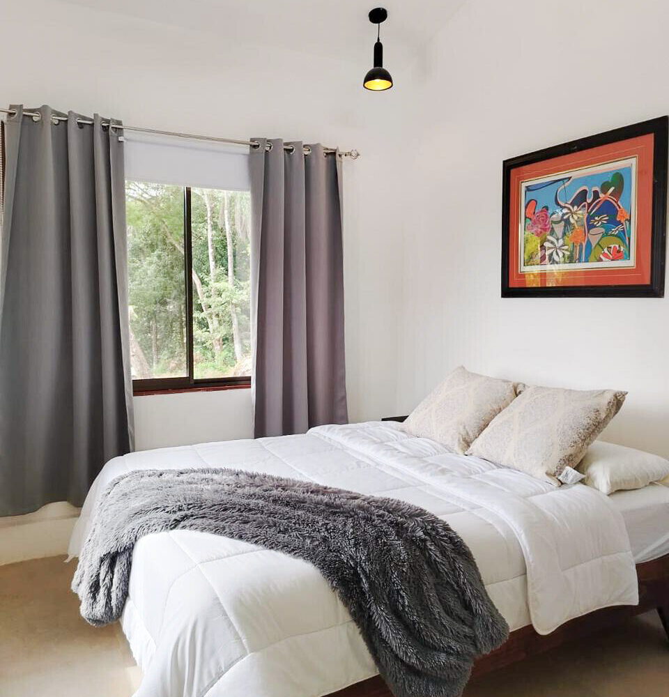 Bedroom with a window framing the surrounding forest