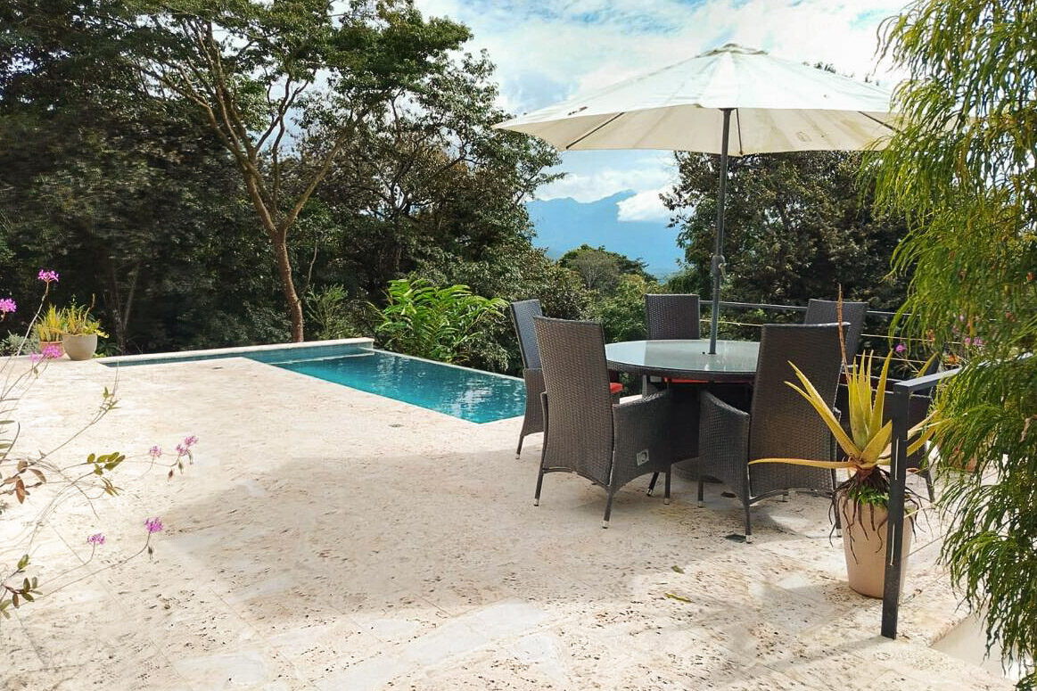 Shaded poolside dining table under a parasol