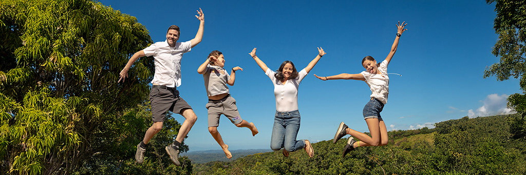 The Kuster family jumping together on a hilltop above the valley