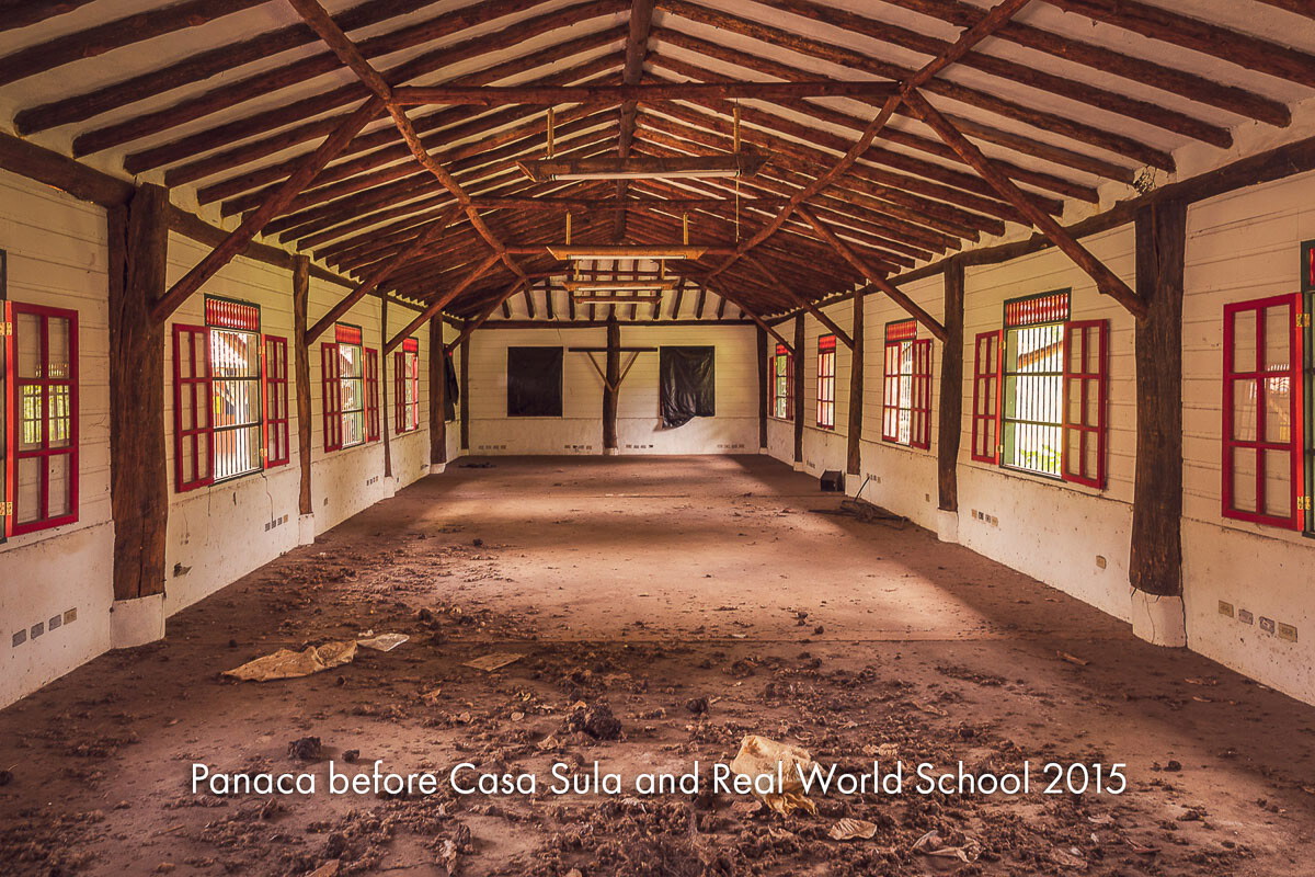 A long empty hall with a timber roof and red-framed windows
