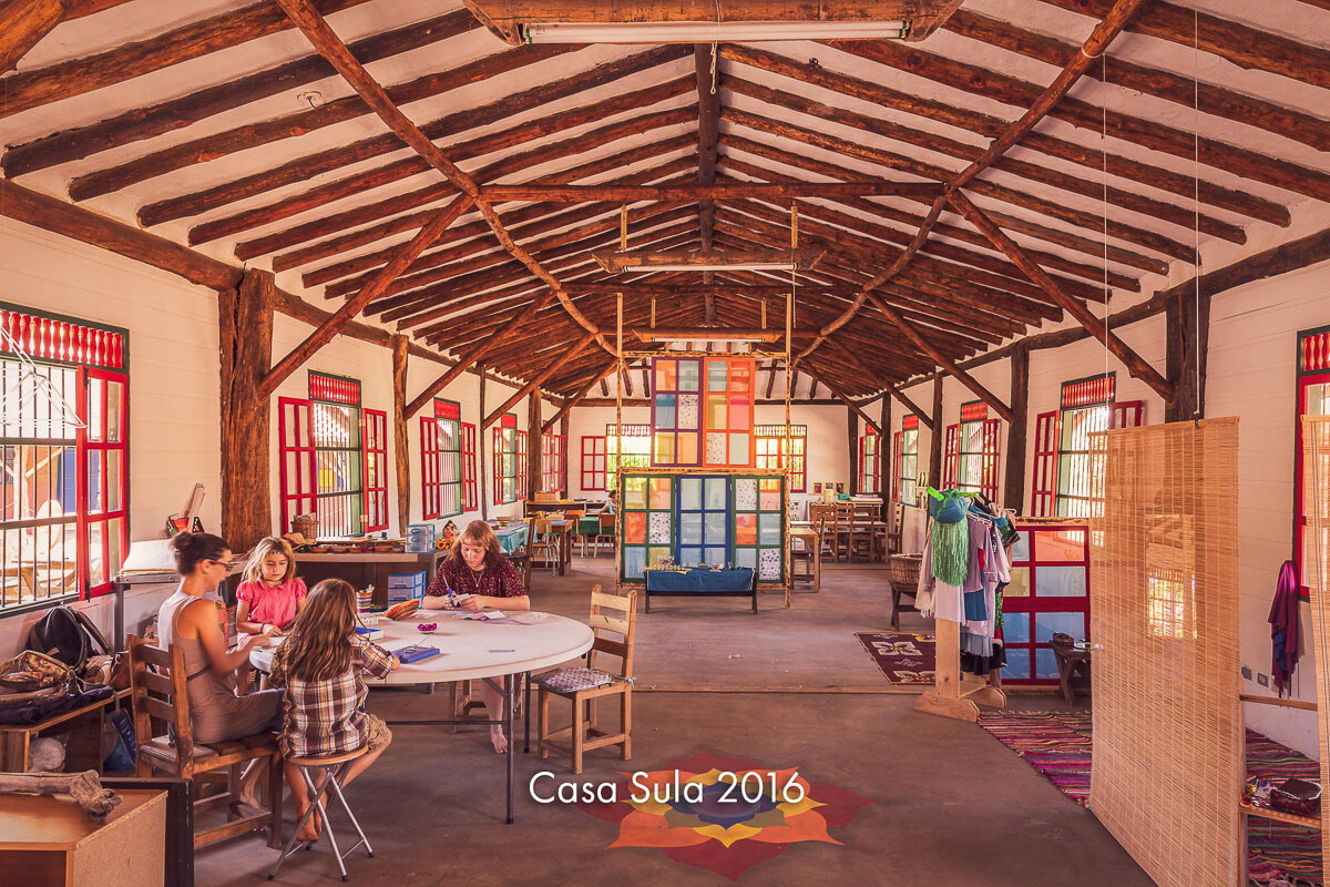 An open timber classroom where children and adults work at tables