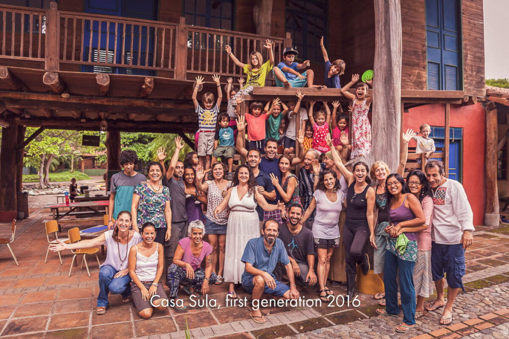 A large group of families gathered together on the steps of a red building