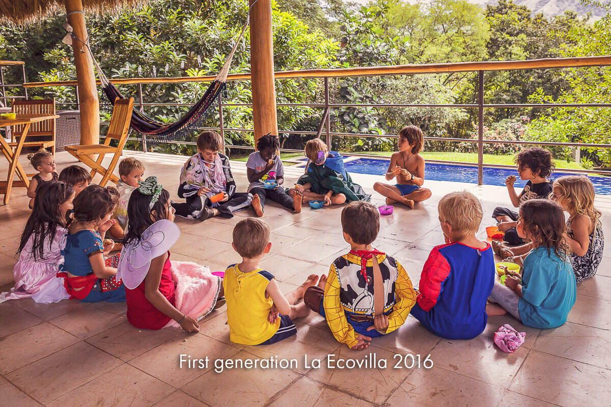 Children sitting in a circle on a terrace beside a pool