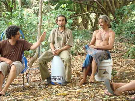 Three men playing drums together under the trees