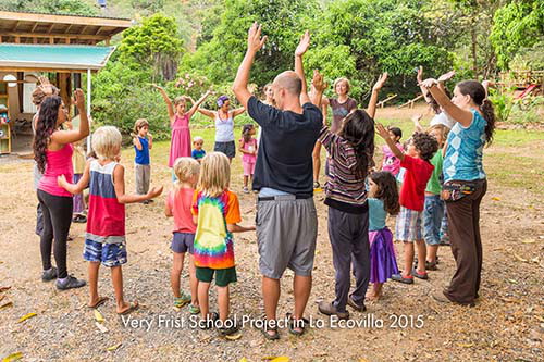Adults and children standing in a circle with their arms raised