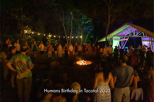 People gathered around a fire at night under strings of lights
