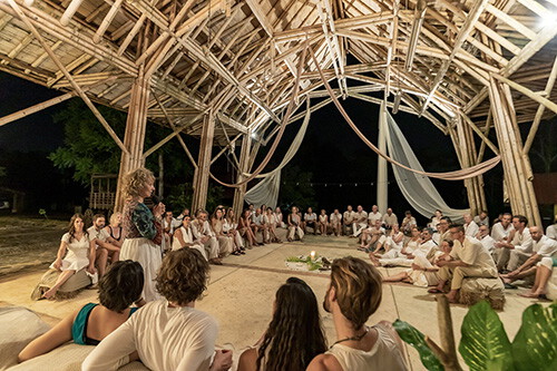 People seated on the floor of a bamboo dome during a gathering