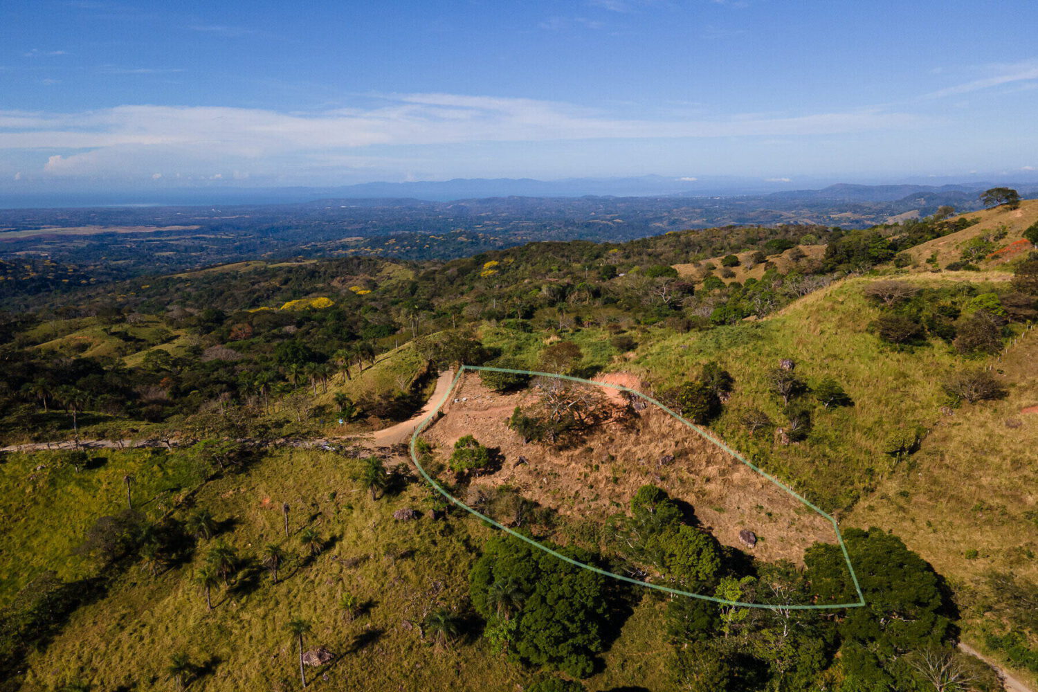 Aerial view over green hills folding into a wide valley
