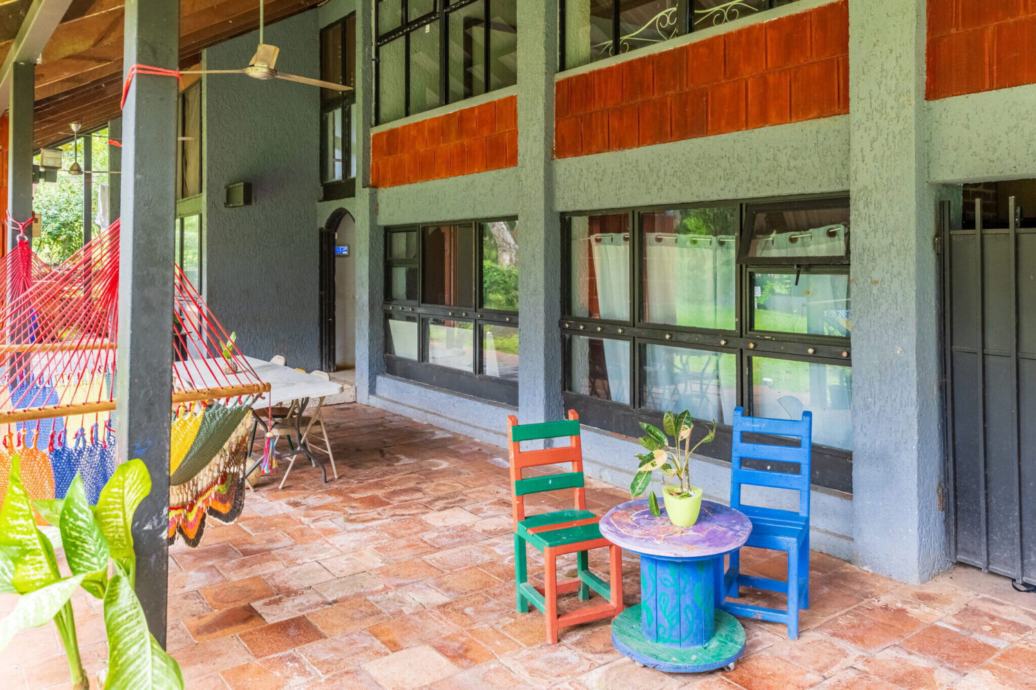 Covered veranda of the existing building with a hammock and seating